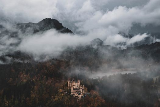 Mysterious view of Hohenschwangau Castle surrounded by mist in Bavarian Alps, Germany.