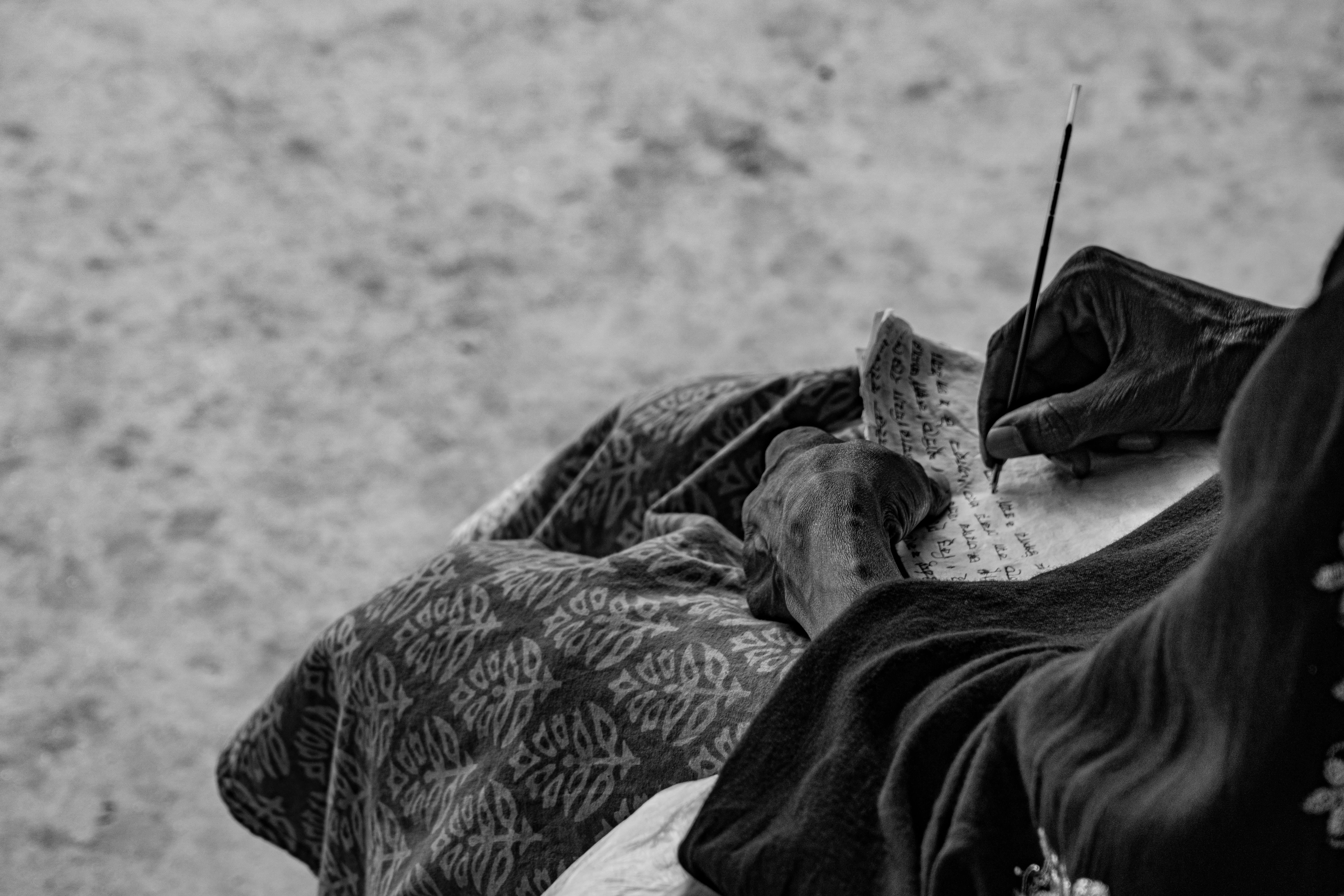 Kostnadsfria En person skriver på papper med traditionellt bläck, fångat i svartvitt. Stock foto