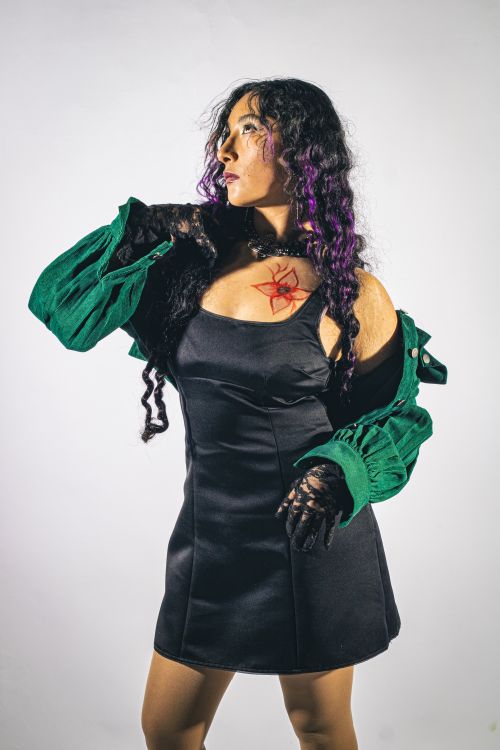 Free Artistic portrait of a woman posing confidently in a black dress with ornate makeup and green jacket. Stock Photo