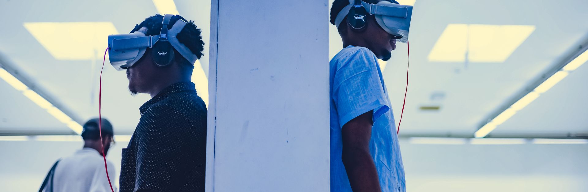 Two men using VR headsets in a modern indoor gallery setting.