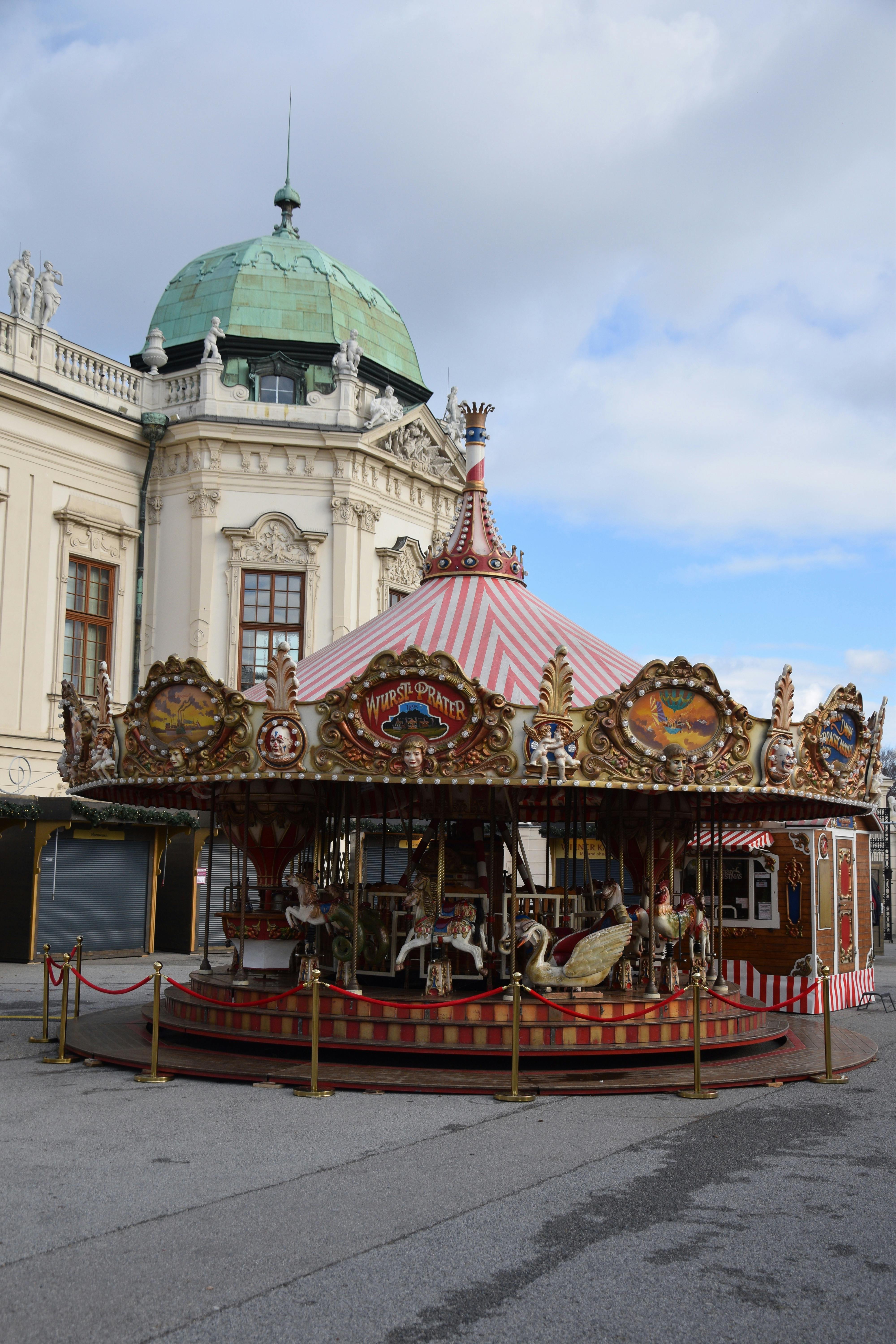 Charming vintage carousel near a historic building on a sunny day.