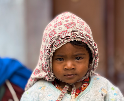 Close-up portrait of a young child in Kathmandu, wearing traditional clothing with a patterned hood.