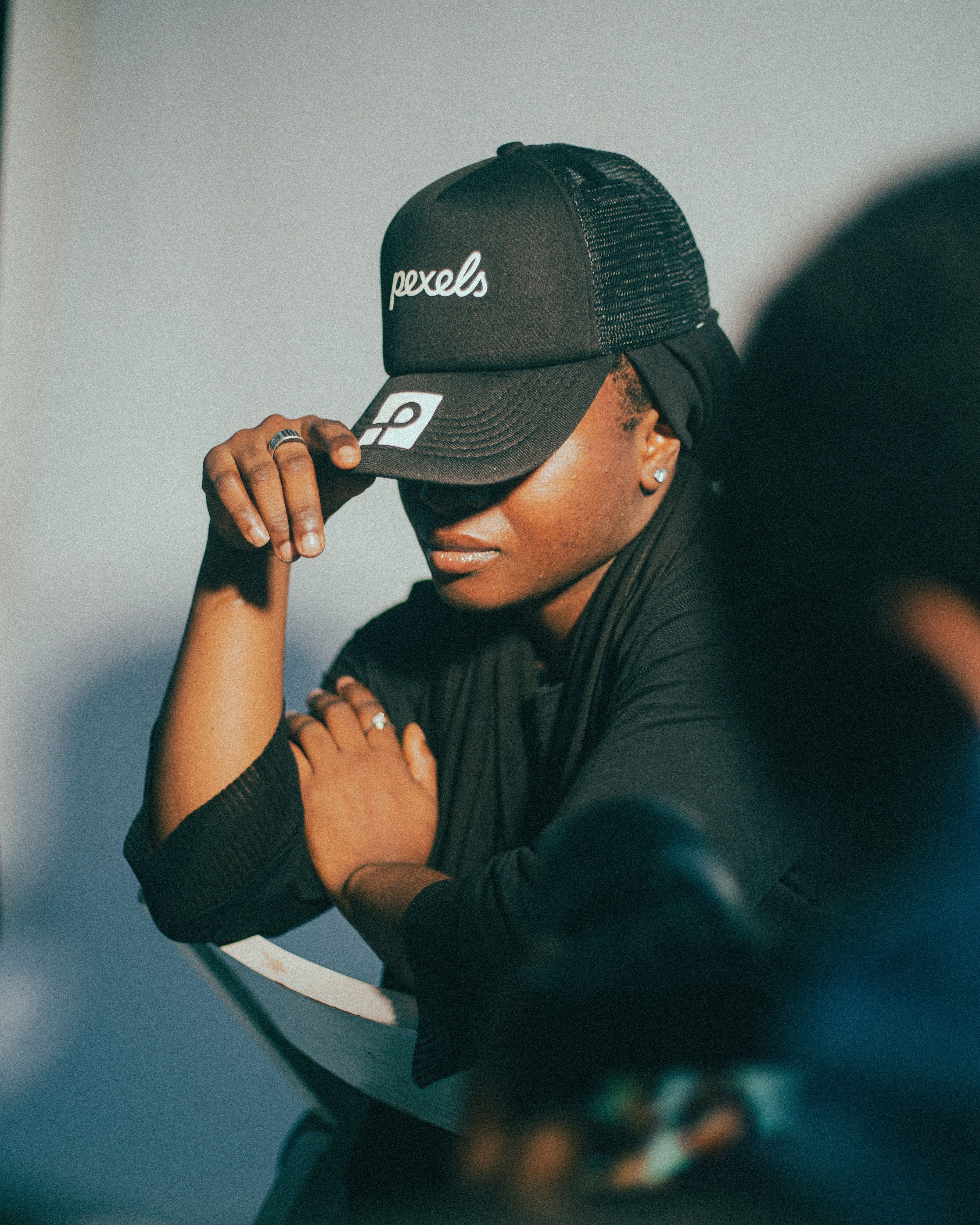 A stylish person wearing a hat with a pensive pose in a modern setting.