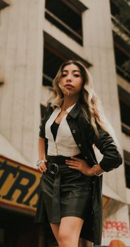 Confident young woman in trendy outfit poses in city environment, embodying modern fashion.