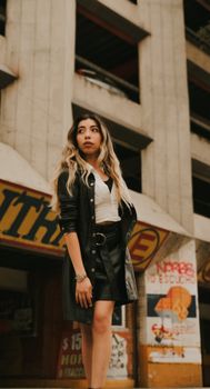 A stylish young woman in urban settings, showcasing trendy fashion with a confident pose.