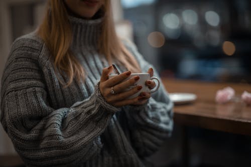 Wanita Dengan Sweater Rajut Abu Abu Memegang Mug Keramik Putih
