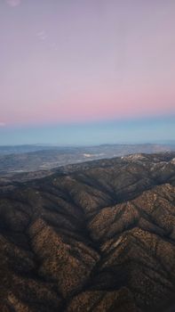 Scenic twilight view of mountain range with pink and blue sky from above.
