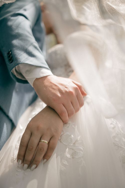 Free Intimate close-up of a couple's hands, showcasing wedding rings and romantic bond. Stock Photo