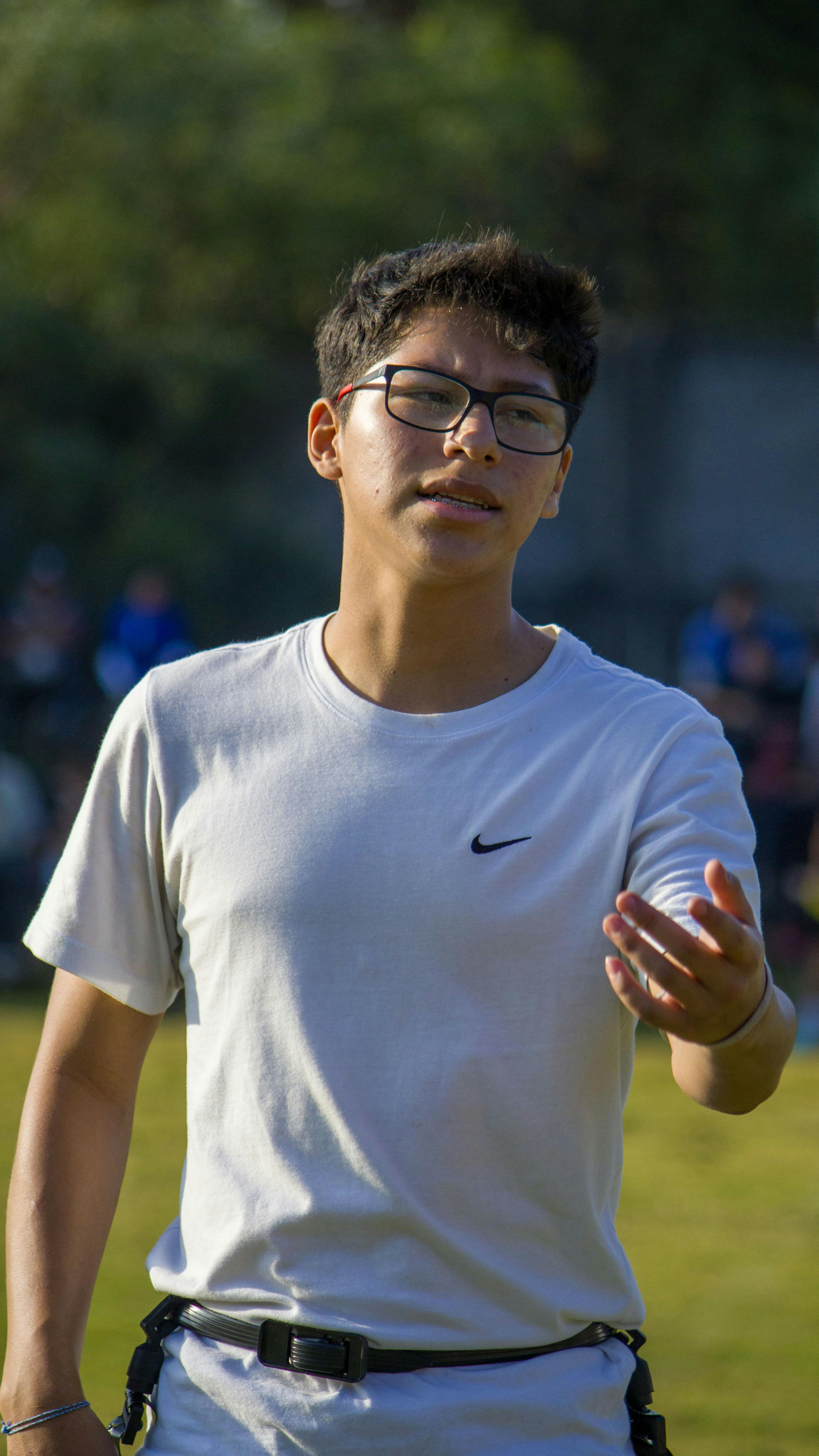 A young man in a white shirt, glasses, participating in an outdoor sports activity.