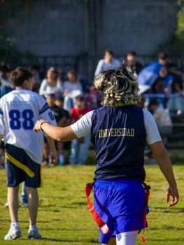 University students engaged in a friendly game of flag football during a sunny day on campus.
