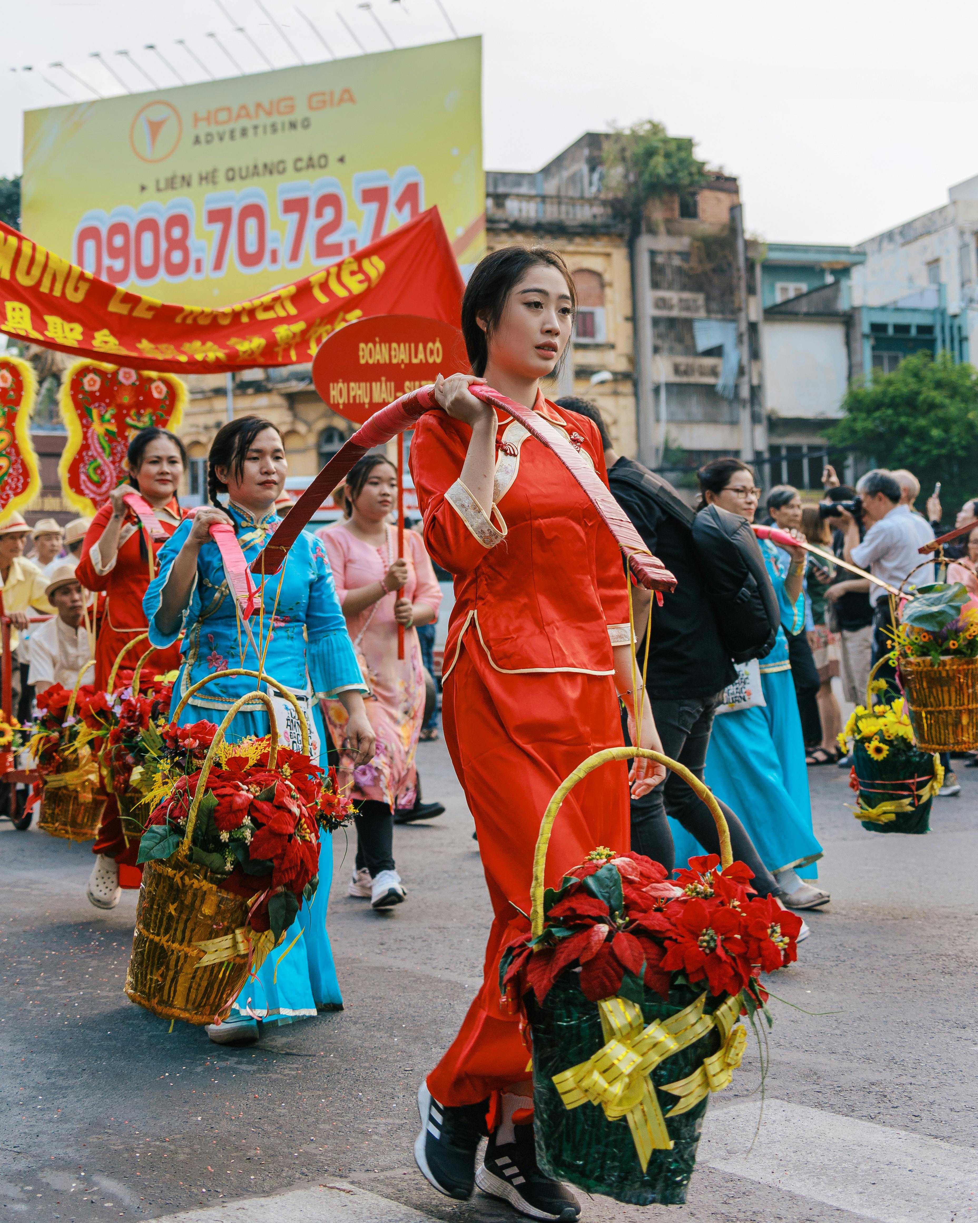 Vibrant street festival in Ho Chi Minh City with women in traditional attire carrying decorated baskets.