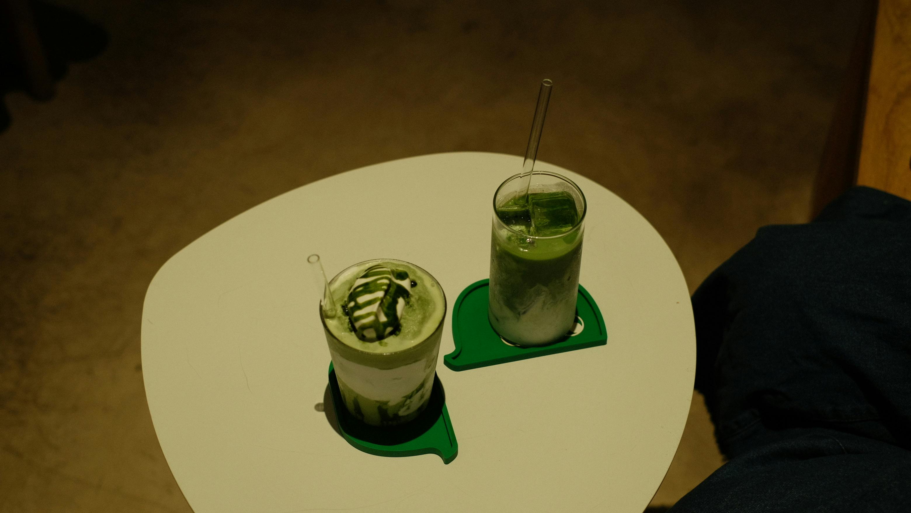 無料 ミニマルなセッティングの白いテーブルの上に、クリエイティブな抹茶ドリンク 2 杯。 写真素材