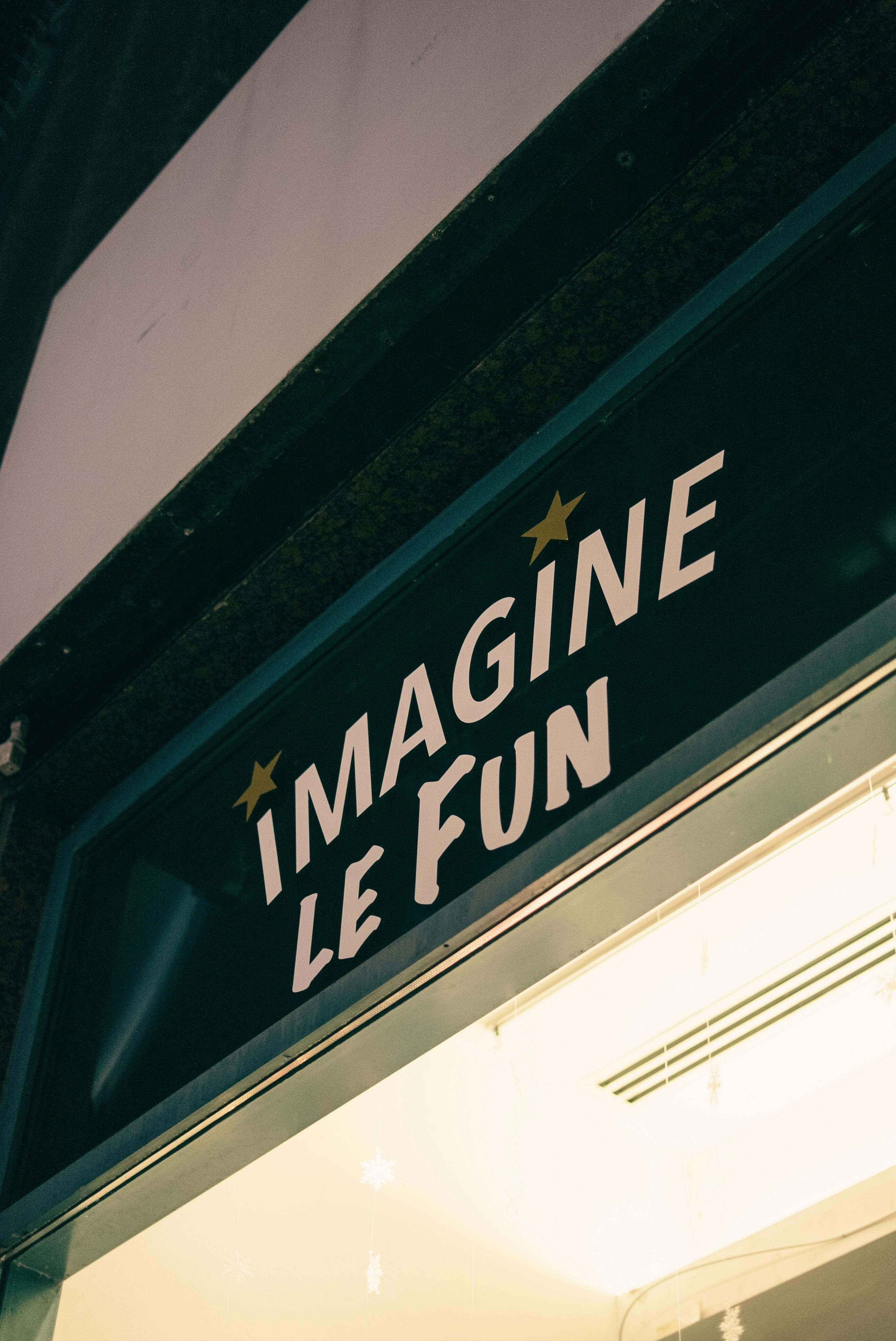 Close-up of 'Imagine Le Fun' shop sign illuminated at night, showcasing urban nightlife charm.