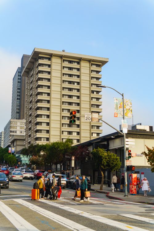 Free Crowded intersection in city, people crossing with luggage under skyscraper. Stock Photo