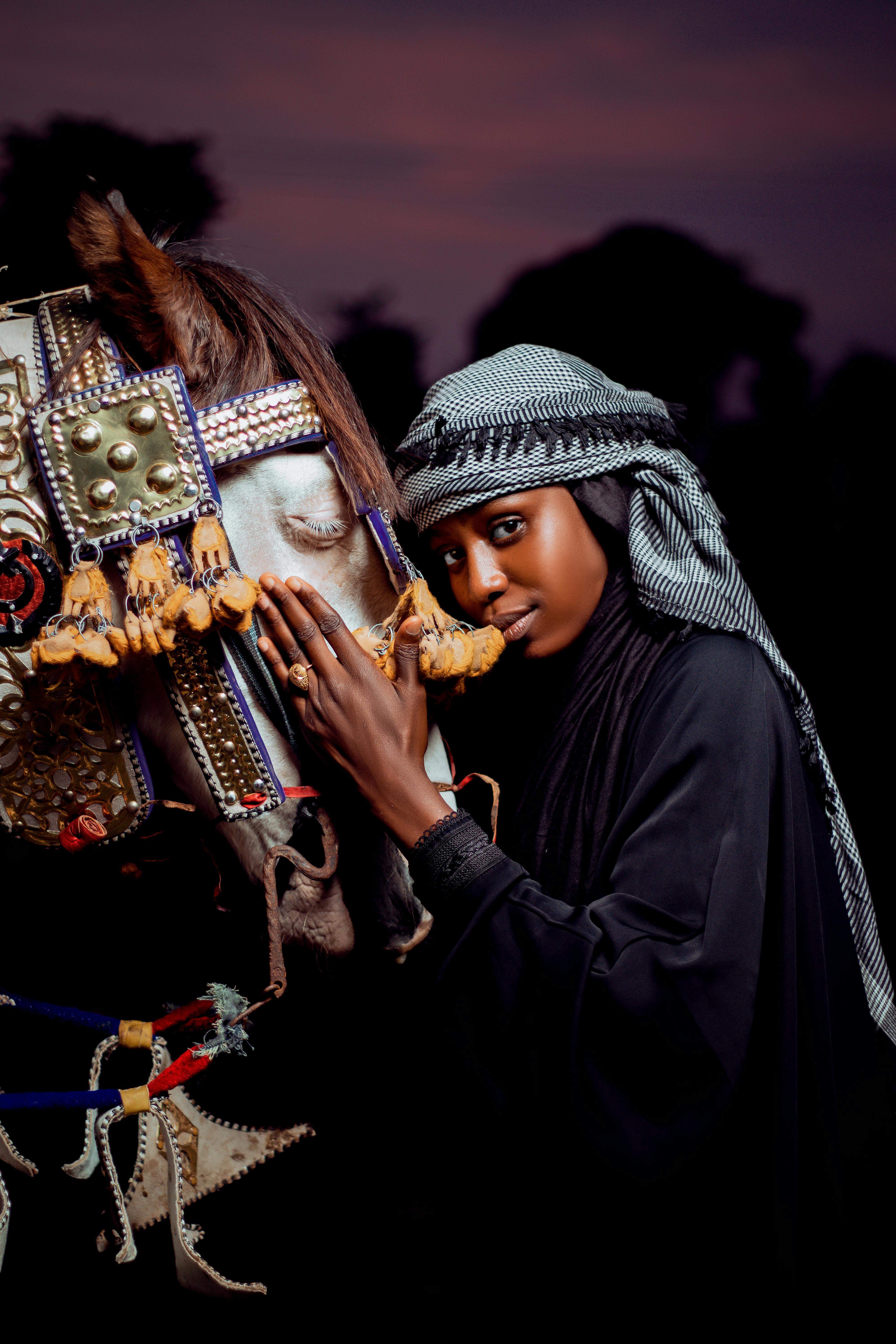 Portrait of a woman with a traditionally adorned horse at twilight, exuding elegance.