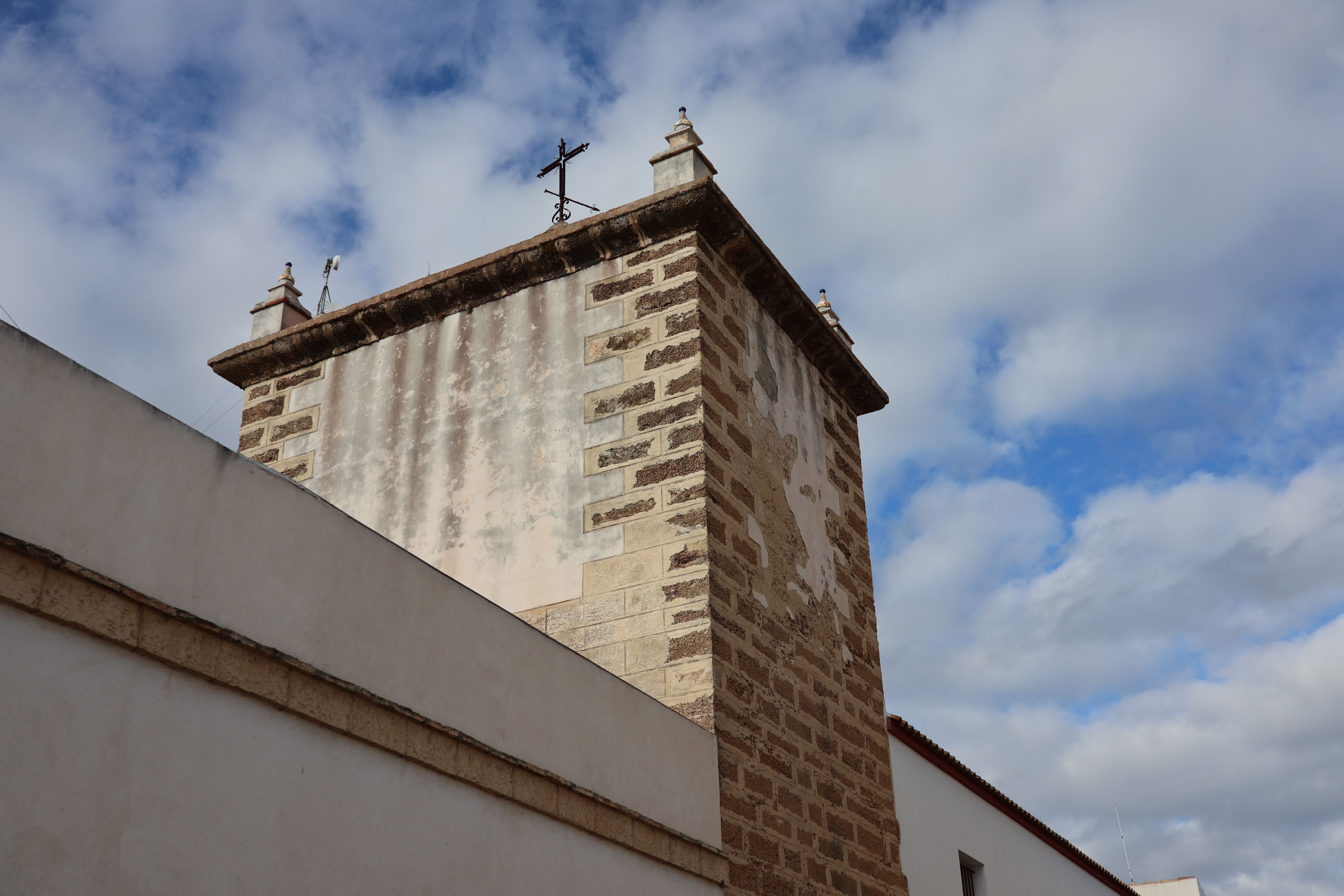 A detailed view of a historic tower in Puerto Real, Andalucía against a vibrant sky.