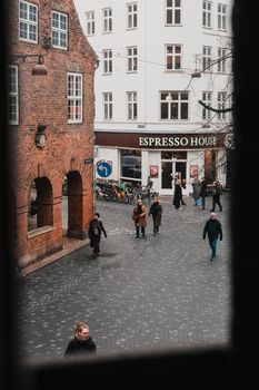 People walking in a cobblestone street of Copenhagen, near Espresso House, during early winter.