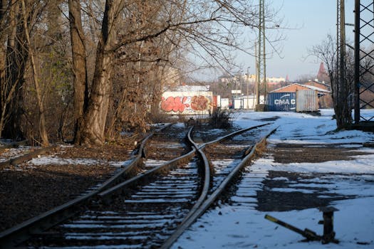 Abandoned railway tracks in winter with snow and graffiti in urban setting.