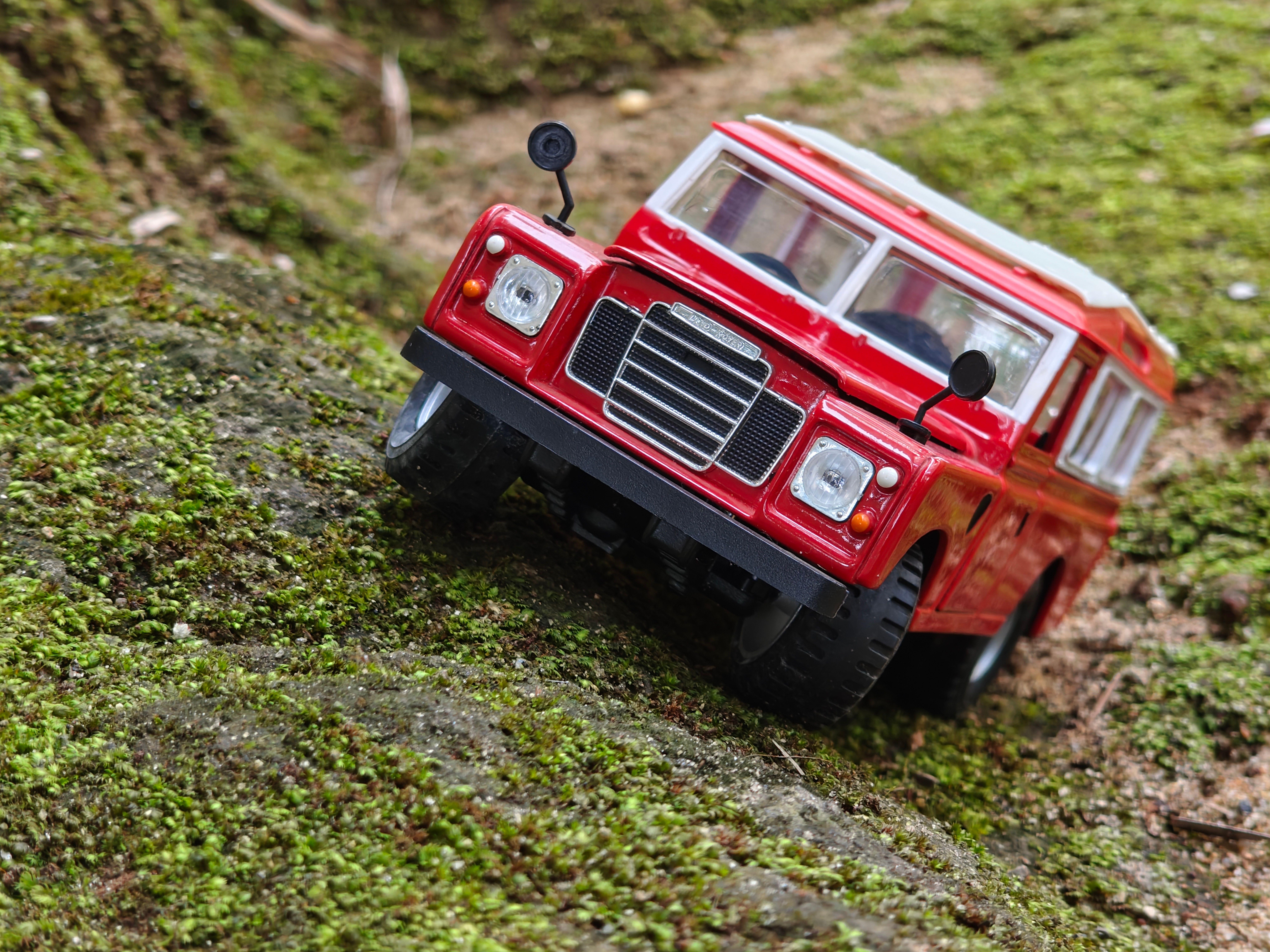 Diecast model of an off-road vehicle on a moss-covered slope.