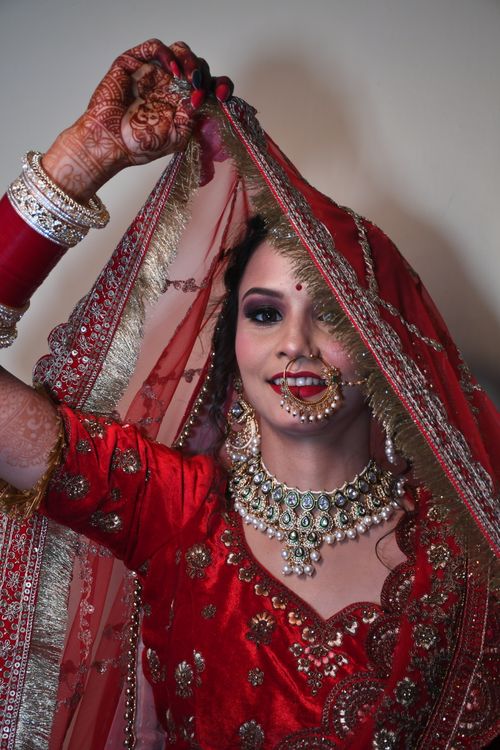 Free Elegant Indian bride in red lehenga with intricate jewelry and henna, radiating joy. Stock Photo