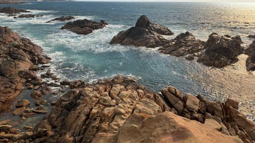 Free A breathtaking view of a rocky coastline with ocean waves crashing dramatically at sunset. Stock Photo