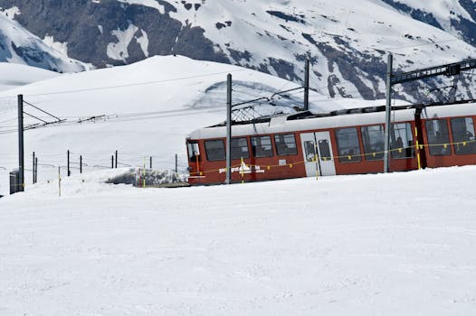 Red train traverses snowy terrain in the Swiss Alps, showcasing stunning winter views.