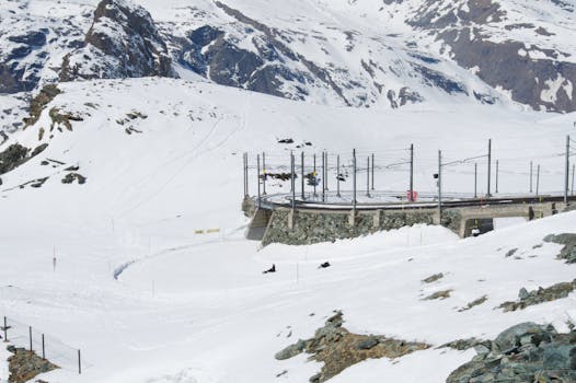 Gornergrat Railway winding through snow-covered Swiss Alps near Zermatt with scenic mountain backdrop.