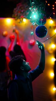 A young man reaching for colorful lights during a vibrant night celebration.