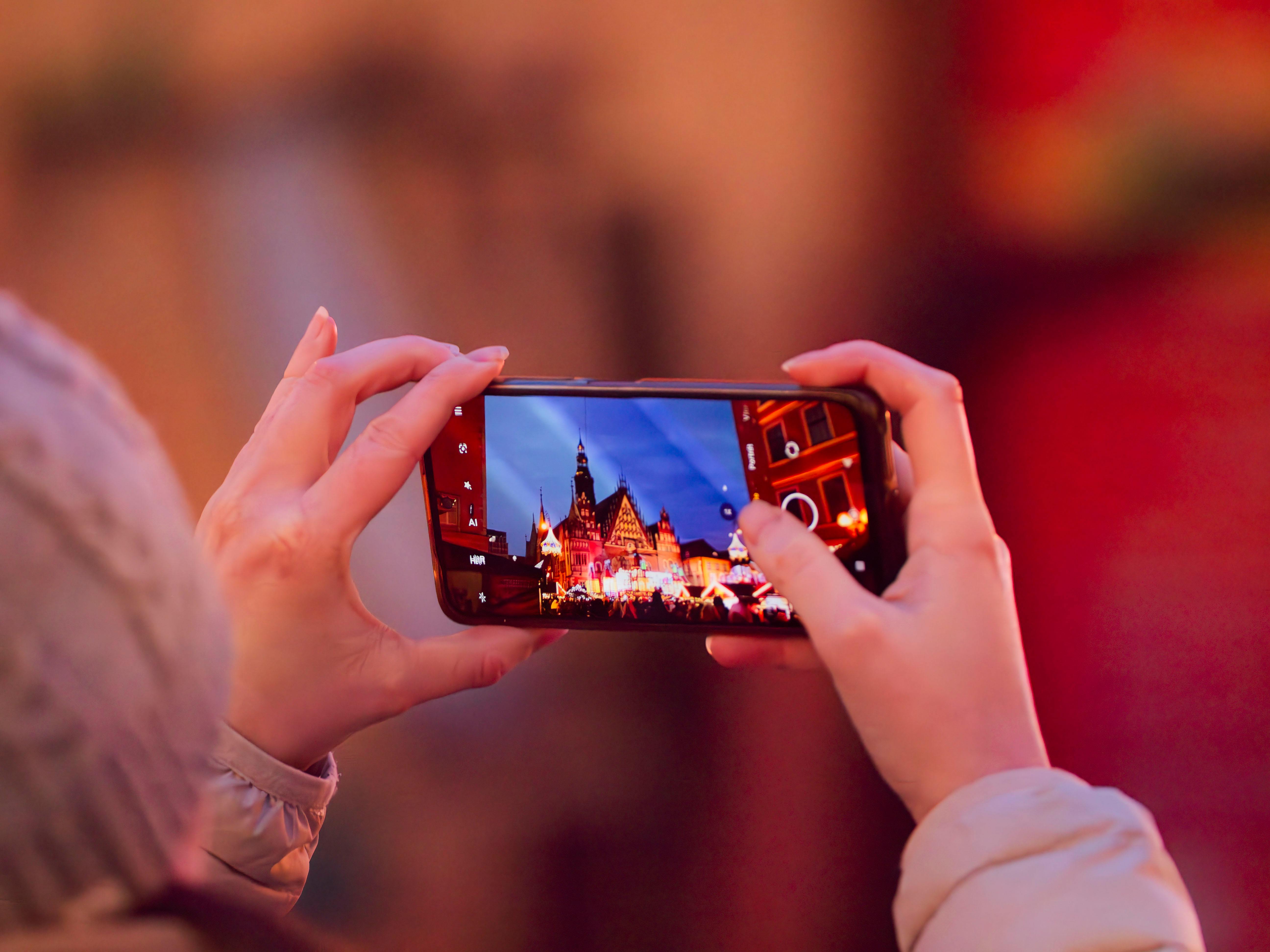 A smartphone captures Wrocław's festive market square with a vibrant evening glow.