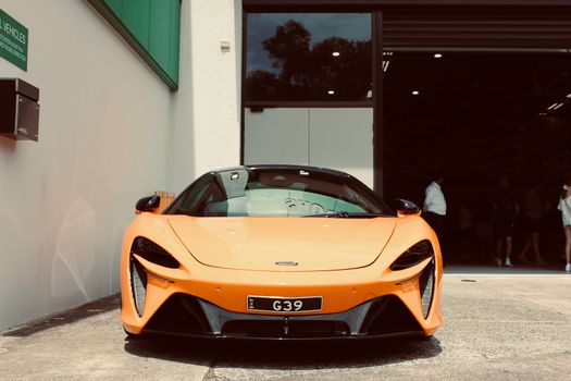 Stunning orange sports car showcased at showroom entry, capturing luxury and elegance.