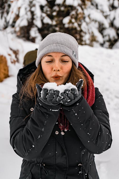 Woman Blowing Snow From Her Hands