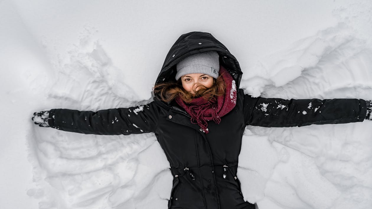 Frau In Schwarzer Jacke Und Grauer Strickmütze Auf Schneebedecktem Boden