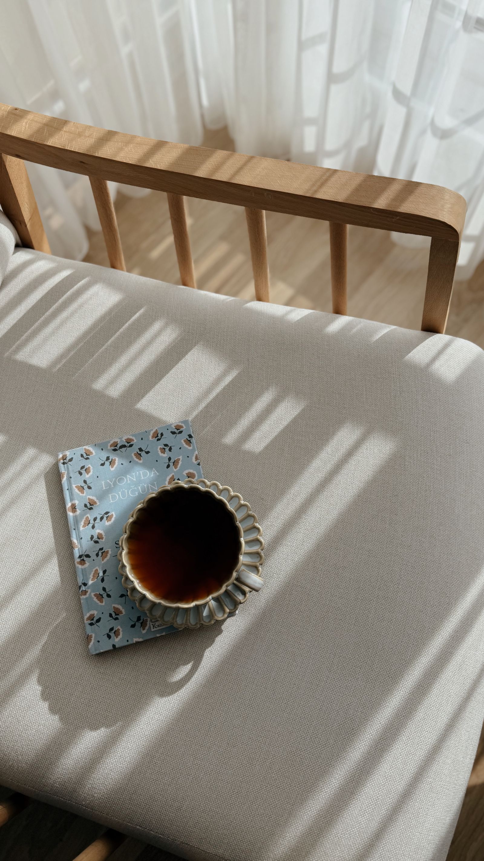 A cup and a book on a sunlit linen chair