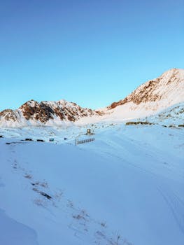 A scenic view of snowy mountains and a clear sky at sunrise, creating a serene atmosphere.