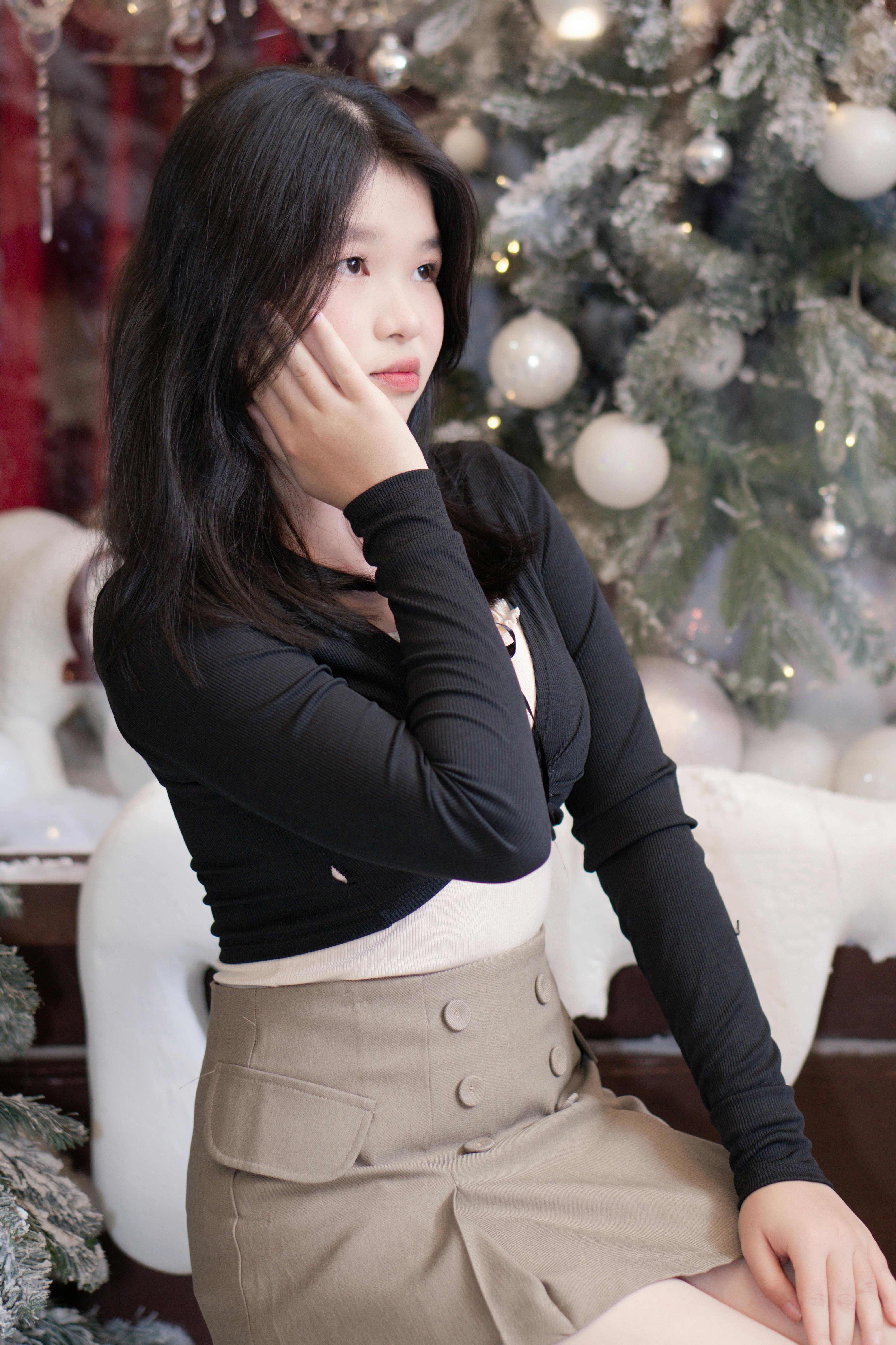 Young woman in a festive setting near Christmas decorations, thoughtfully posing.