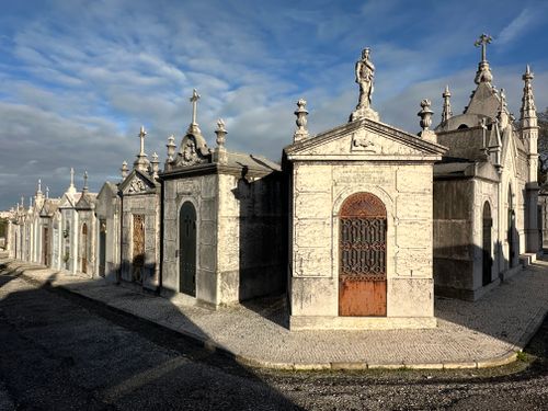 Free Row of ornate mausoleums in a historic cemetery in Lisbon, Portugal, under a bright blue sky. Stock Photo