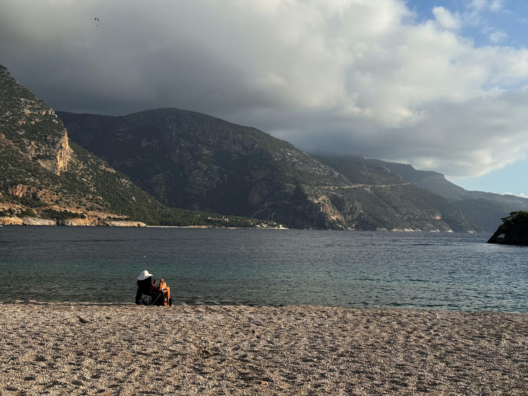 Tranquil beach scene with mountains and cloudy sky in Fethiye, Turkey.