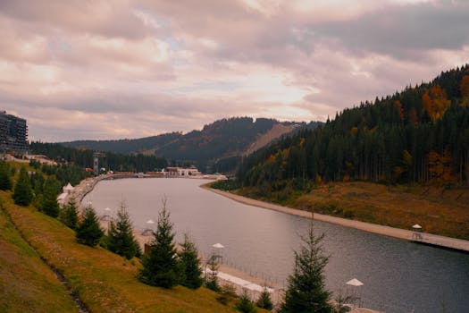 Majestic lake surrounded by autumn forest and mountains under a vibrant sky.