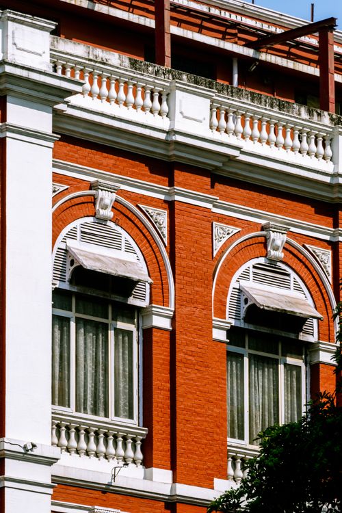Free A classic red brick building facade with ornate white detailing and arched windows. Stock Photo