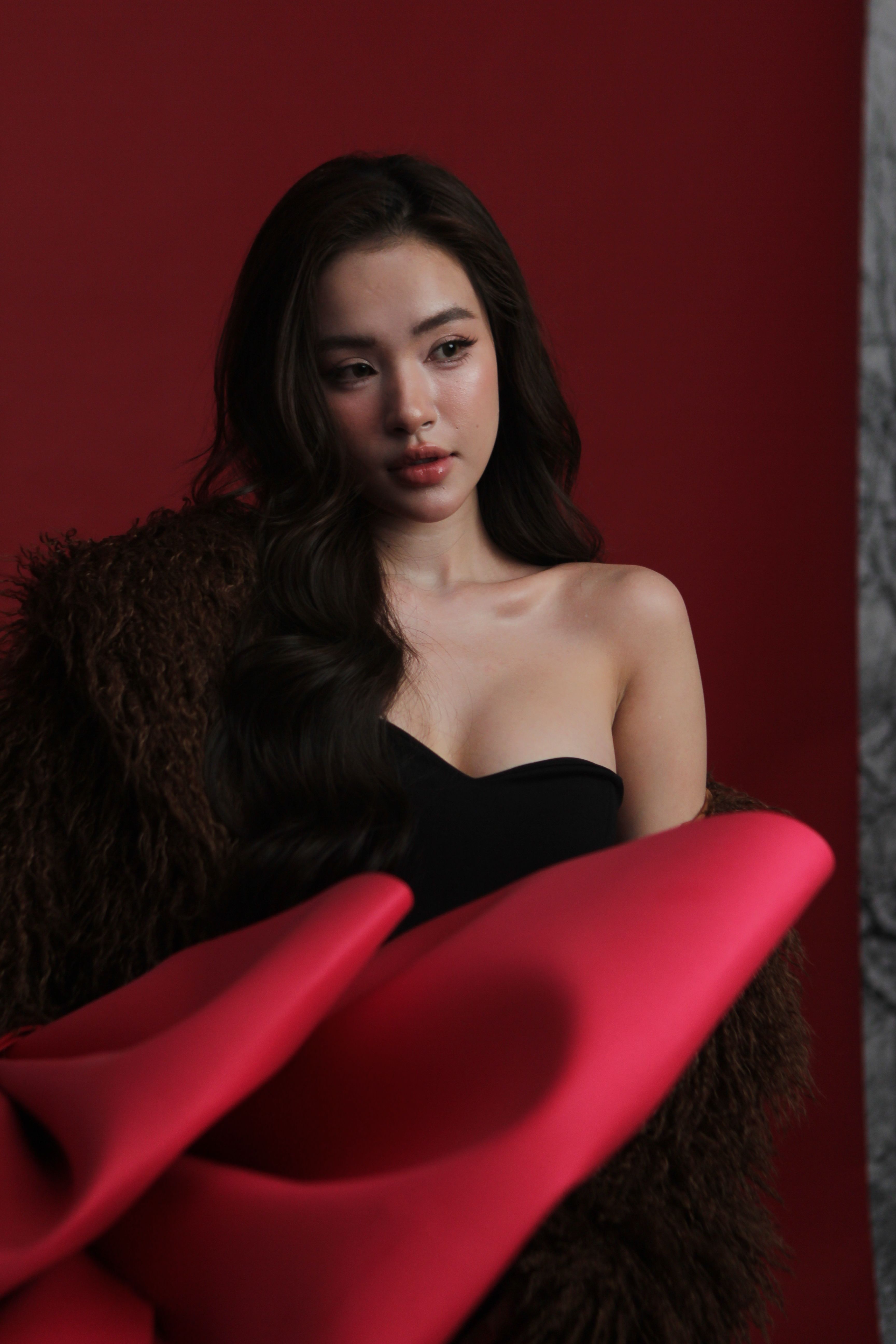 Stylish portrait of a woman in a dark, elegant setting with vibrant fashion contrasts.