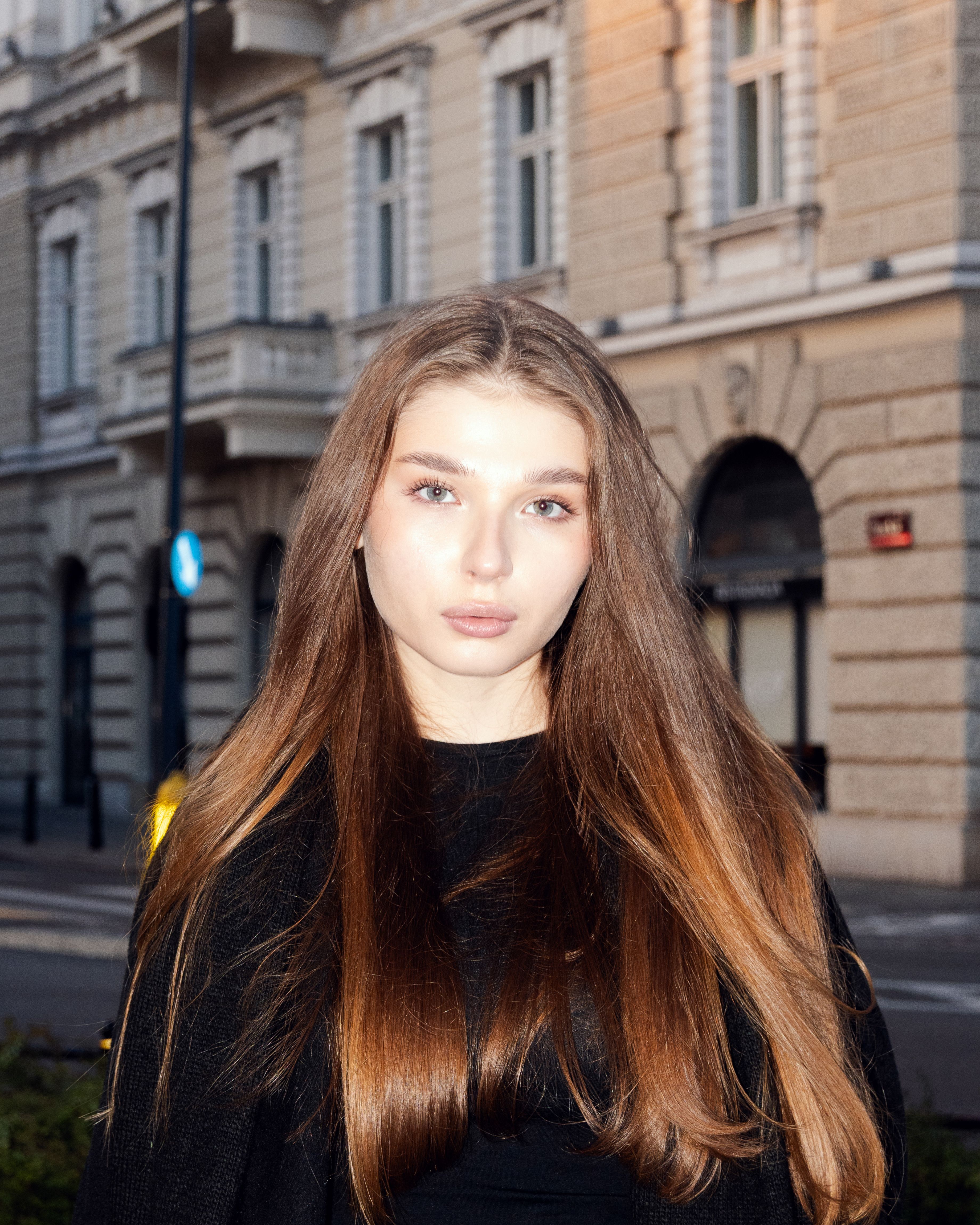Portrait of a young woman with long hair on a city street background, emphasizing beauty and fashion.