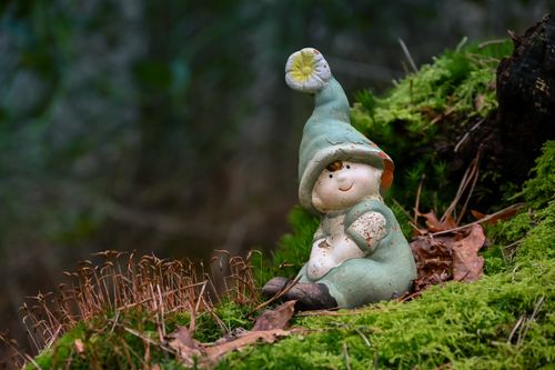 Free Adorable elf figurine resting on moss in a serene forest setting, perfect for a whimsical touch. Stock Photo
