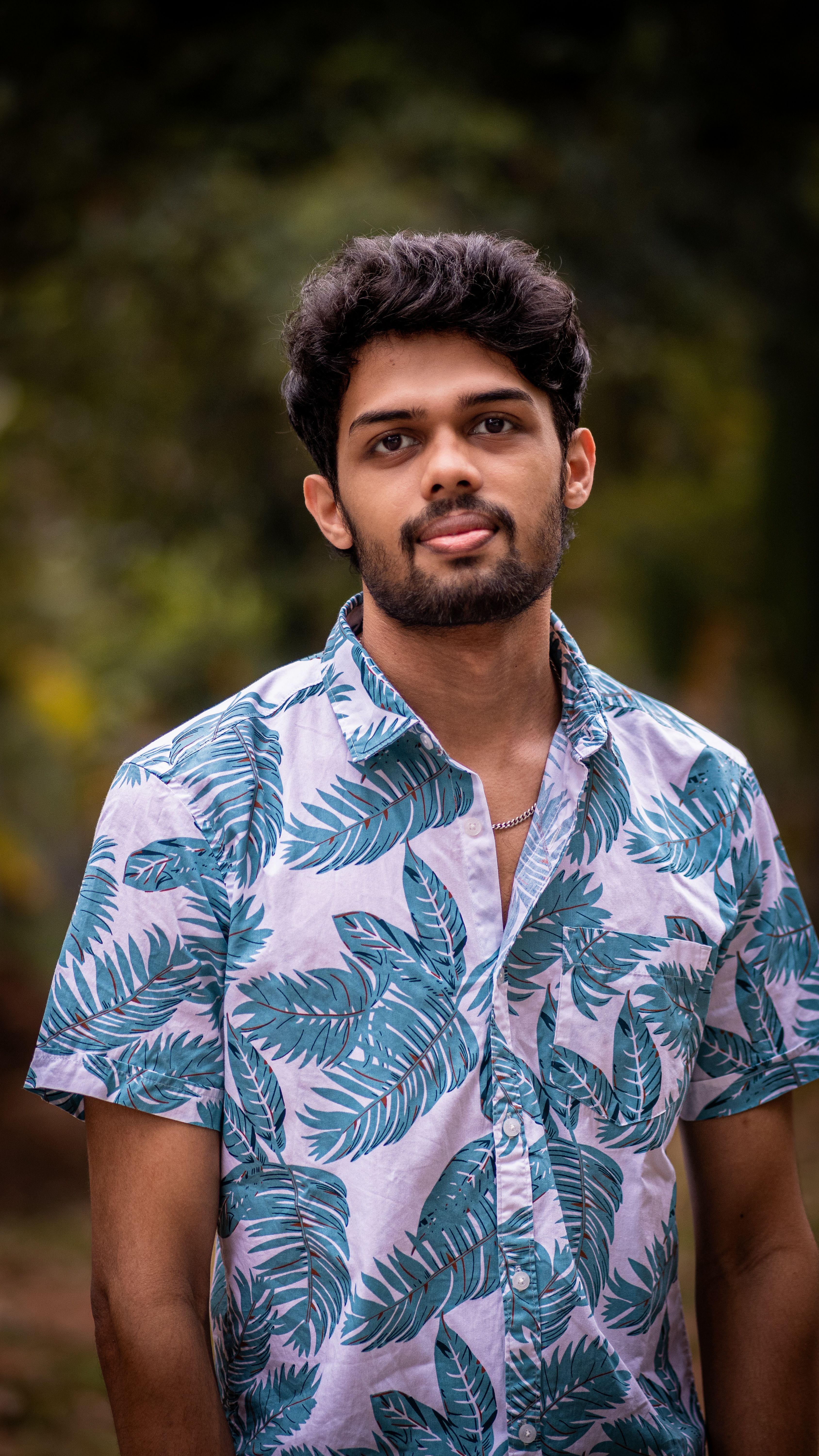 Portrait of a young man with a tropical shirt in an outdoor natural setting, looking at the camera.