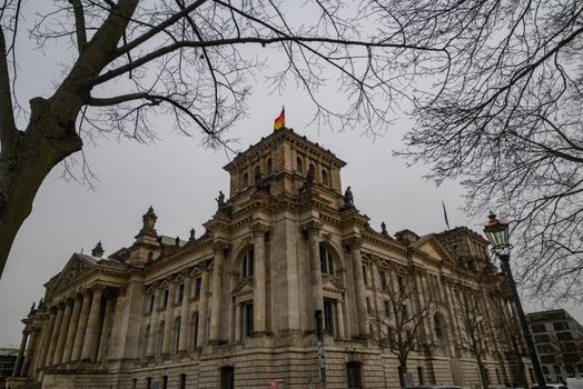 View of the iconic Reichstag building in Berlin, Germany, framed by bare winter trees.