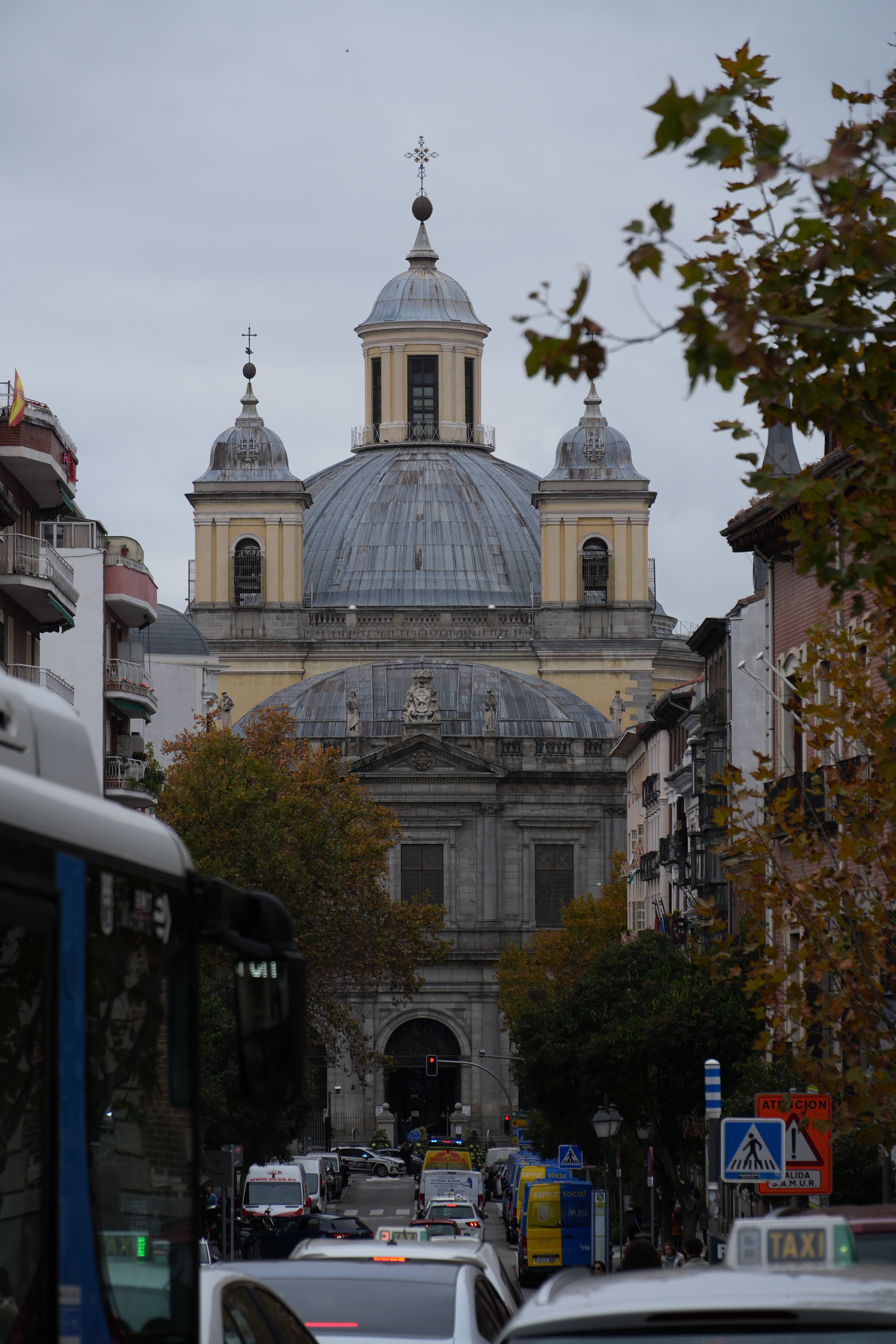 Street view of San Francisco el Grande Basilica in Madrid with autumn trees and city life.