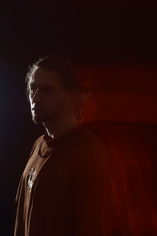 Free Mysterious male portrait with dramatic red and black lighting creating a moody atmosphere. Stock Photo