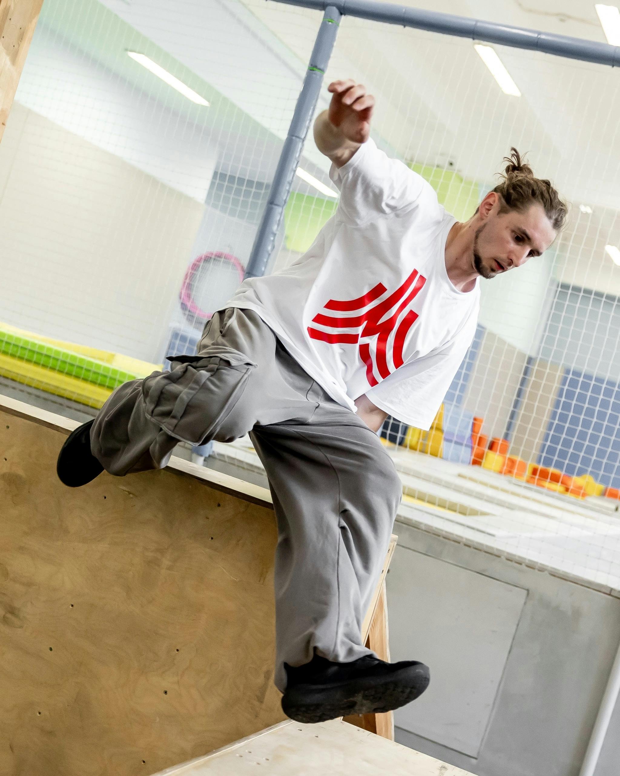 Energetic young man doing parkour jump indoors with focus on movement.