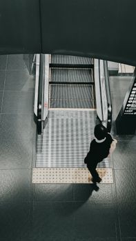 Top view of a person walking near an escalator in a contemporary indoor setting.