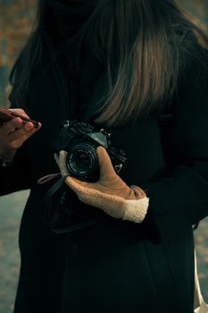 Close-up of a woman with an analog camera and smartphone outdoors in Duisburg, Germany.