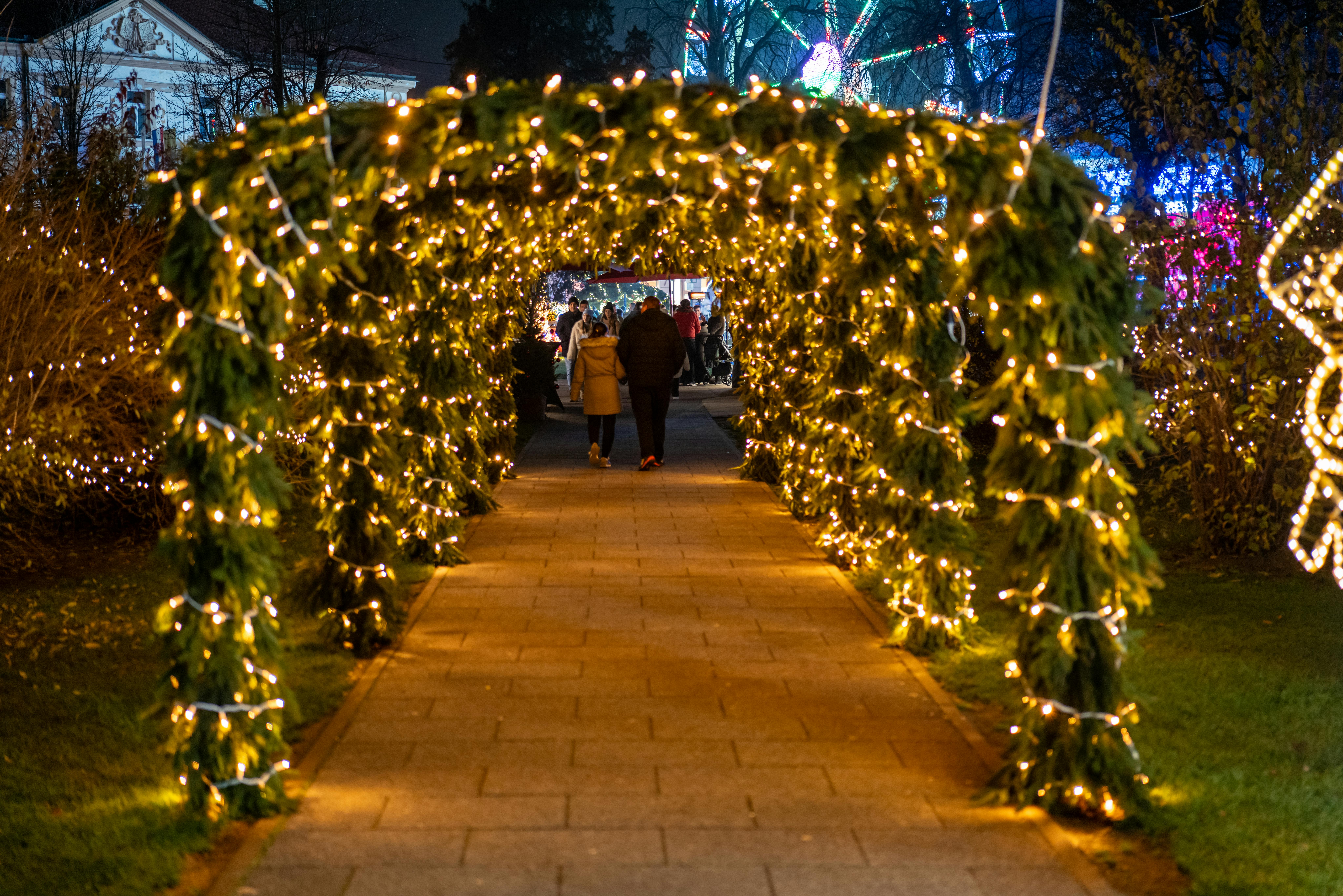 A beautifully lit archway with people walking underneath during a festive night in Bjelovar.